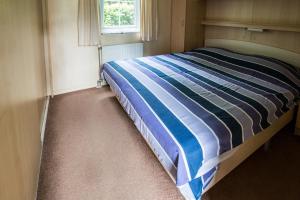 a bedroom with a bed with a blue and white striped comforter at Chalet vakantie Wageningen in Wageningen