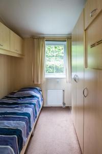 um pequeno quarto com uma cama e uma janela em Chalet vakantie Wageningen em Wageningen