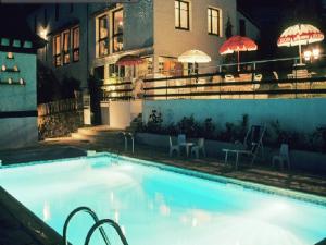 une grande piscine devant un immeuble la nuit dans l'établissement LOGIS HOTEL Les Tilleuls, à Saint-Cirgues-de-Jordanne