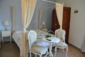 a bedroom with a bed and two chairs and a table at La Casa nel Borgo in Bibbona