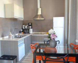 バルセロナにあるFeel at Sants Apartmentsのキッチン(ガラステーブル、オレンジの椅子付)