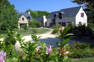 a house with a driveway and flowers in the foreground at Le Tertre Gatinais in Saint-Briac-sur-Mer