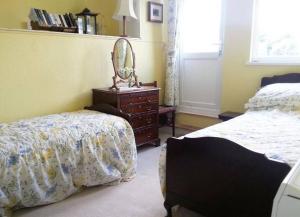 a bedroom with two beds and a dresser with a mirror at TopHeavy Cottage Mevagissey in Mevagissey