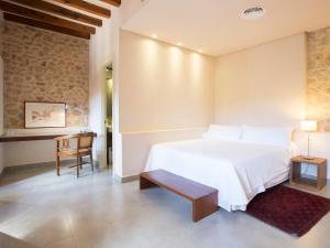1 dormitorio con 1 cama blanca grande y 1 silla en Ca' n Beia Suites - Adults Only, en Alaró