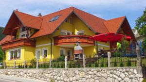 a yellow house with an orange roof and a fence at Apartments and Rooms With View on Bled in Bled