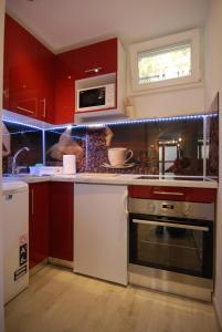 cocina con armarios rojos, fogones y microondas en Apartment Maria en Split