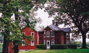 czerwony dom z drzewami przed nim w obiekcie Strawberry Farm B and B w mieście Muscatine