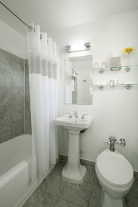 a white bathroom with a toilet and a sink at Essex House Hotel in Miami Beach