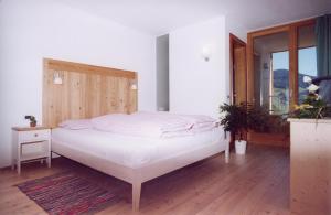 a bedroom with a white bed with a wooden headboard at Al Cargà in San Vigilio Di Marebbe