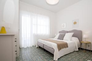 a white bedroom with a bed and a window at Angelina Apartments Amalfi Coast in Maiori