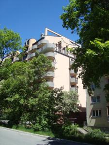 a tall white building with trees in front of it at Apartament BB in Krynica Zdrój