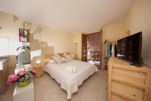 a bedroom with a bed and a flat screen tv at El Faro Apartaments in Tarragona