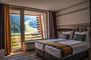 a bedroom with a bed and a large window at Hotel Han Bjelašnica in Bjelašnica