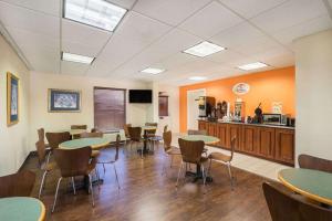 Super 8 by Wyndham Knoxville North/Powell في نوكسفيل: غرفة طعام مع طاولات وكراسي ومطبخ