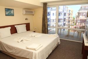 a bedroom with a bed and a large window at Salena Hotel in Primorsko