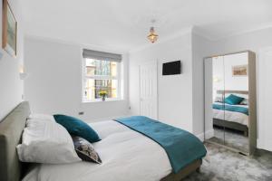 a white bedroom with a bed and a mirror at Ocean Outlook - Broadstairs Best! in Broadstairs