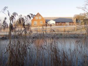 a farm with a house and a fence and water at Pension Roager in Jejsing