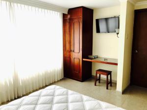 a bedroom with a bed and a tv and a table at Hotel Azuay in Duitama +6 photos