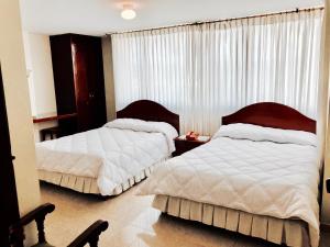 1 dormitorio con 2 camas y una ventana con cortinas en Hotel Azuay, en Duitama