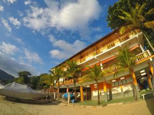 a building on the beach with a boat next to it at Pousada da Praia in Mangaratiba