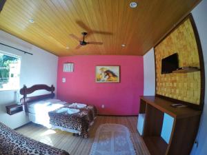 1 dormitorio con pared de color rosa, cama y techo en Pousada da Praia, en Mangaratiba