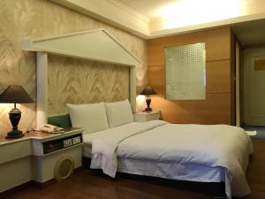 a bedroom with a large bed and a table with a phone at Zaw Jung Business Hotel in Taichung