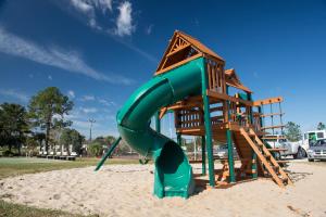 a playground with a green slide in the sand at Orlando RV Resort in Orlando