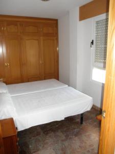 a bedroom with a white bed and wooden cabinets at Edificio Mirasierra in Oropesa del Mar