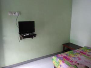 a bedroom with a flat screen tv on the wall at Titan's Greenhouse in Banyuwangi