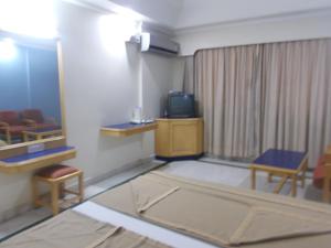 a room with a room with a tv and chairs at Modern Hotel in Bangalore