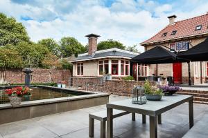 un patio con una mesa y una sombrilla frente a una casa en Guesthouse Villa Emmen, en Emmen