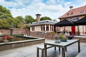 eine Terrasse mit einem Tisch und einem Sonnenschirm vor einem Haus in der Unterkunft Guesthouse Villa Emmen in Emmen