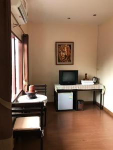 ein Wohnzimmer mit Fernseher und Schreibtisch mit Computer in der Unterkunft Baan Klang Vieng in Chiang Mai
