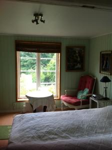 a bedroom with a bed and a chair and a window at Älvbacken in Västerlanda