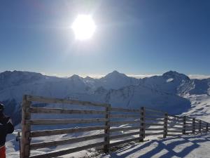 Eine Person steht neben einem Zaun im Schnee in der Unterkunft Hotel Camona & Apart Walserhof in Samnaun