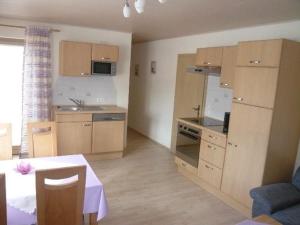 een keuken met houten kasten en een tafel in een kamer bij Gastehaus Helga in Bodenmais