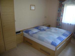 een slaapkamer met een bed met blauwe lakens en een raam bij Gastehaus Helga in Bodenmais