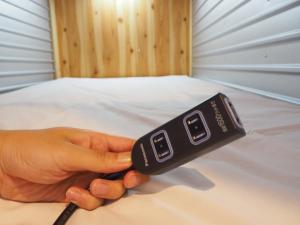 una persona con un mando a distancia en una cama en Hostel Azalea, en Tokio