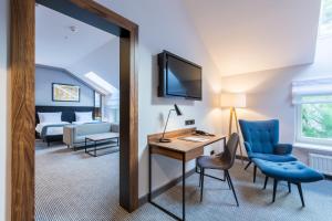 a hotel room with a desk and a bedroom at Grand Ascot Hotel in Kraków