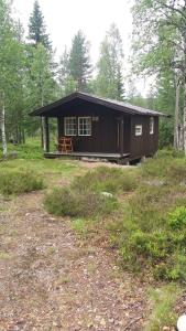 a black cabin in the middle of a forest at Sæteråsen Hytter & Camping Trysil in Trysil