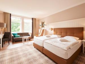 a bedroom with a large bed and a living room at Hotel Munte am Stadtwald in Bremen