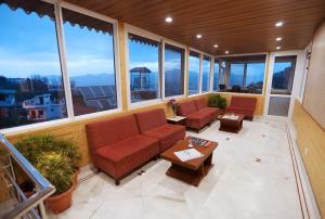 un soggiorno con divani, tavoli e finestre di Hotel Vishnu Palace a Mussoorie