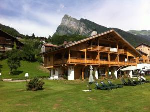 a building with chairs and a mountain in the background at Logis Hotel Gai Soleil in Samoëns