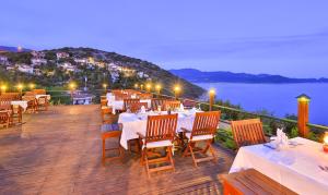 a restaurant with tables and chairs and a view of the water at Diva Residence Allsuite Hotel in Kaş