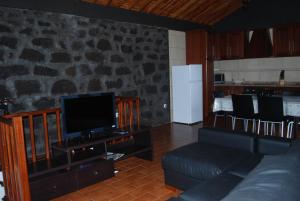a living room with a couch and a tv at Casa do Terreiro in Caminho de Cima