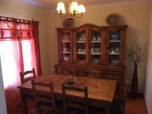 a dining room with a wooden table and a china cabinet at Casa do Almograve in Almograve