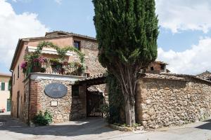 um edifício de pedra com uma árvore em frente em Casalta Boutique Hotel em Monteriggioni