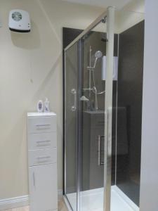 a shower with a glass door next to a dresser at Oaktree Lodge in Doncaster