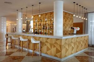 a bar in a hotel lobby with chairs and lights at Palladium Hotel Palmyra - Adults Only in San Antonio