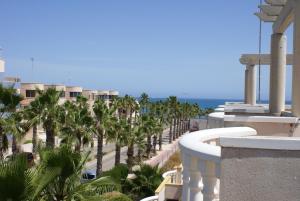 einen Balkon eines Resorts mit Palmen und Meerblick in der Unterkunft Oriheula Costa Cabo Roig 6 in Playas de Orihuela